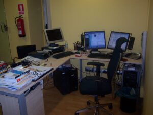 Caótica mesa de despacho con los equipos informáticos